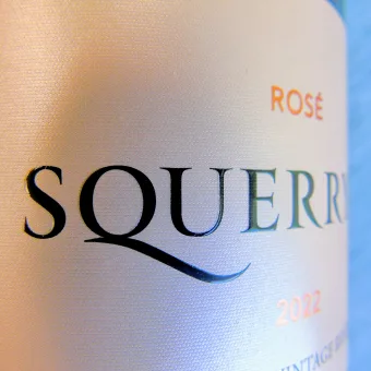Close-up of custom wine label printing with metallic hot foil, raised screen printing and ultra matt varnish on a rosé magnum bottle